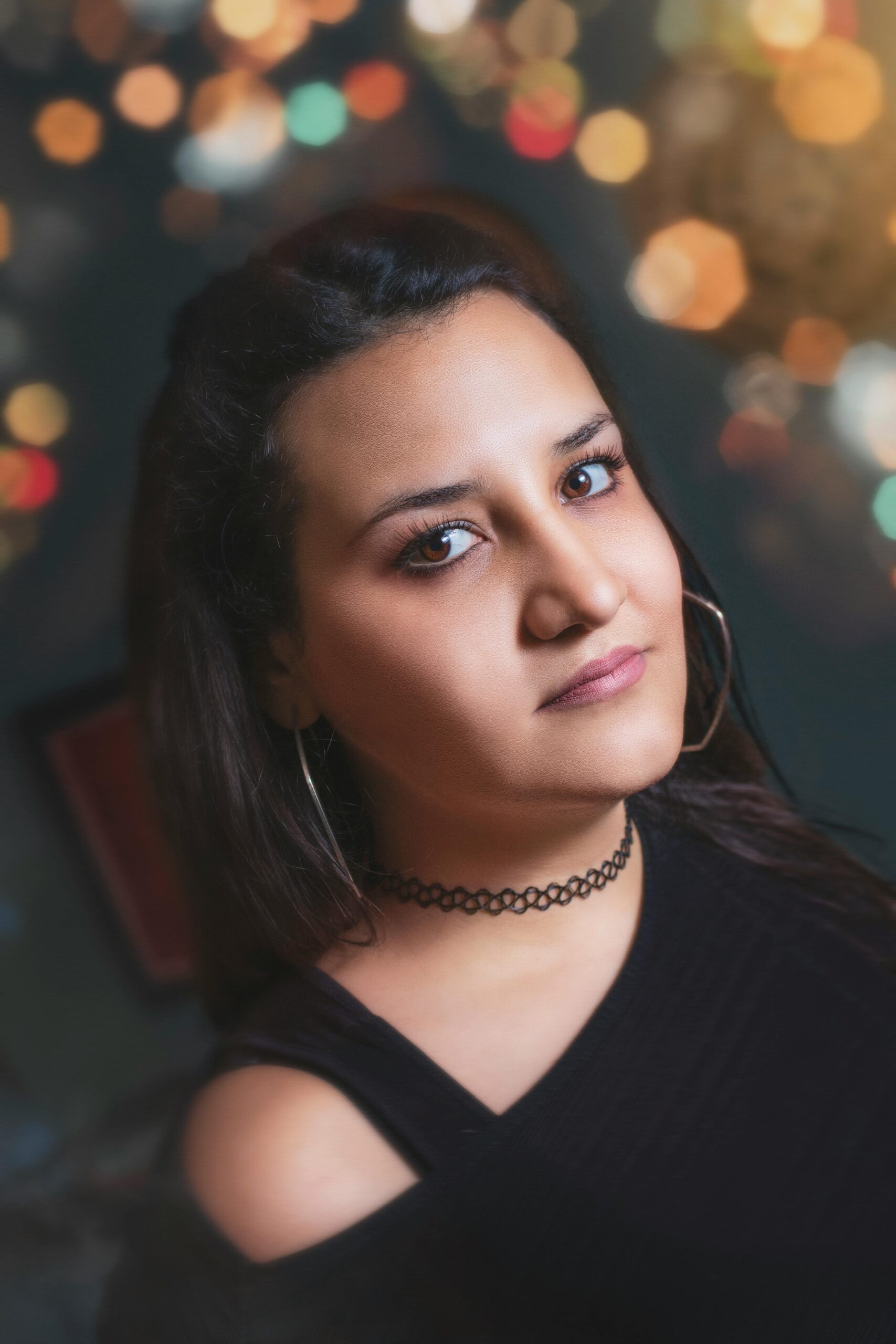 Close-up portrait of a woman in bold fashion with a bokeh backdrop, exuding confidence and style.